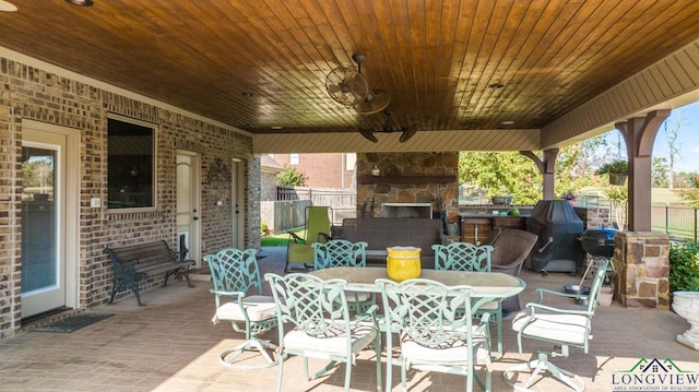 view of patio featuring outdoor dining area, an outdoor stone fireplace, and fence