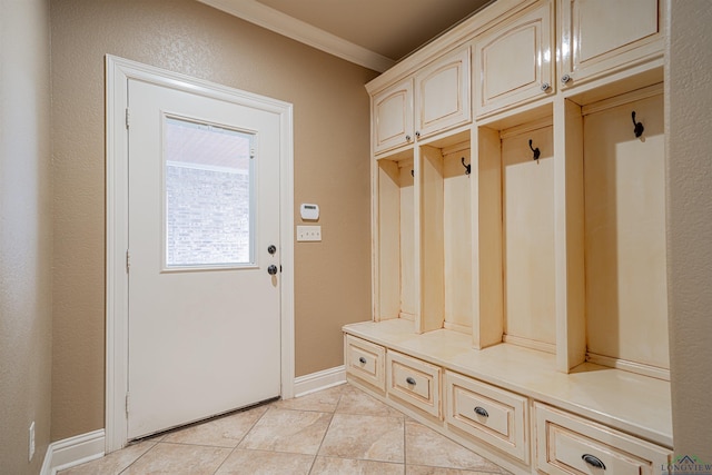 mudroom with crown molding, baseboards, and light tile patterned floors