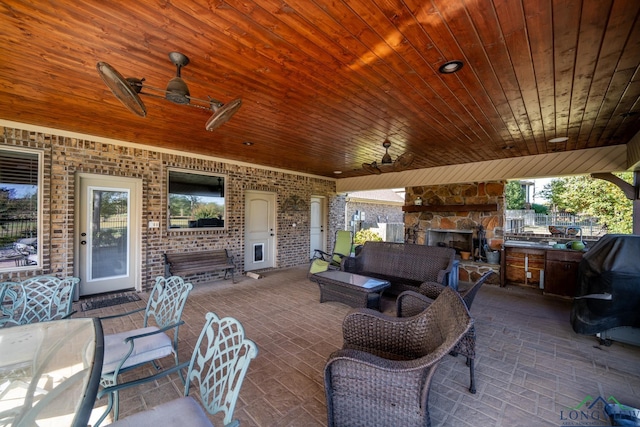 view of patio / terrace with an outdoor living space with a fireplace and a ceiling fan