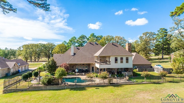 back of house with a patio, a balcony, a fenced backyard, a chimney, and a yard