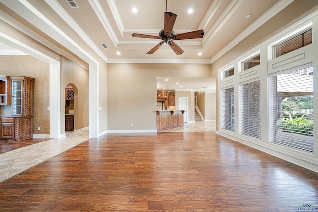 unfurnished living room featuring arched walkways, crown molding, and wood finished floors