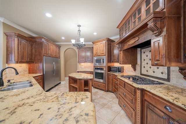 kitchen featuring light stone counters, arched walkways, appliances with stainless steel finishes, ornamental molding, and a sink