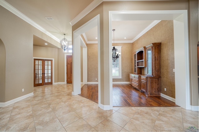 foyer entrance with visible vents, a chandelier, french doors, and ornamental molding