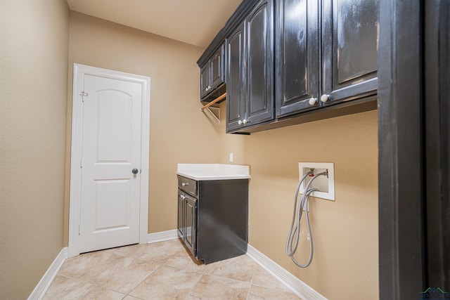 washroom with hookup for a washing machine, cabinet space, baseboards, and light tile patterned floors