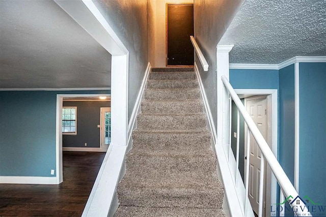 staircase with baseboards, a textured ceiling, wood finished floors, and crown molding