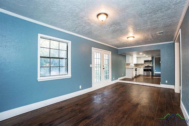 unfurnished living room with dark wood-style flooring, ornamental molding, and baseboards