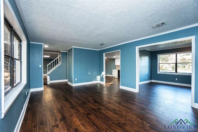 spare room with stairway, ornamental molding, baseboards, visible vents, and wood finished floors