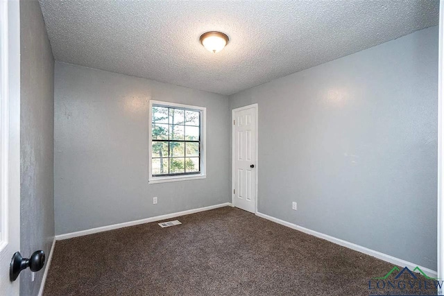 spare room with baseboards, visible vents, dark colored carpet, and a textured ceiling