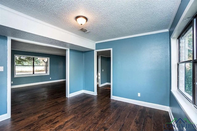 empty room featuring baseboards, visible vents, wood finished floors, and ornamental molding