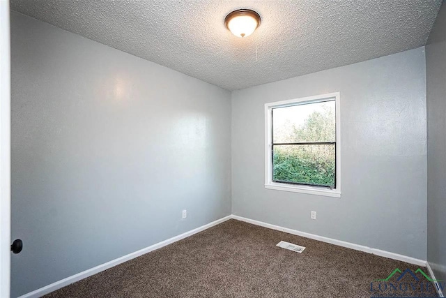 empty room with baseboards, dark carpet, a textured ceiling, and visible vents
