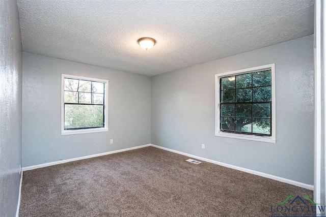 carpeted empty room featuring baseboards, visible vents, and a textured ceiling