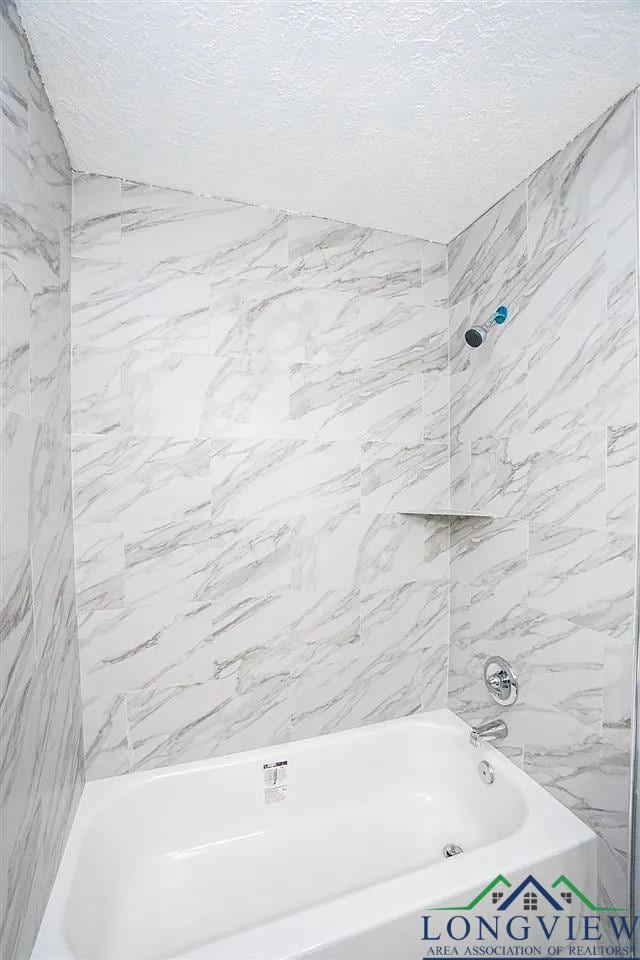 full bathroom featuring bathtub / shower combination and a textured ceiling