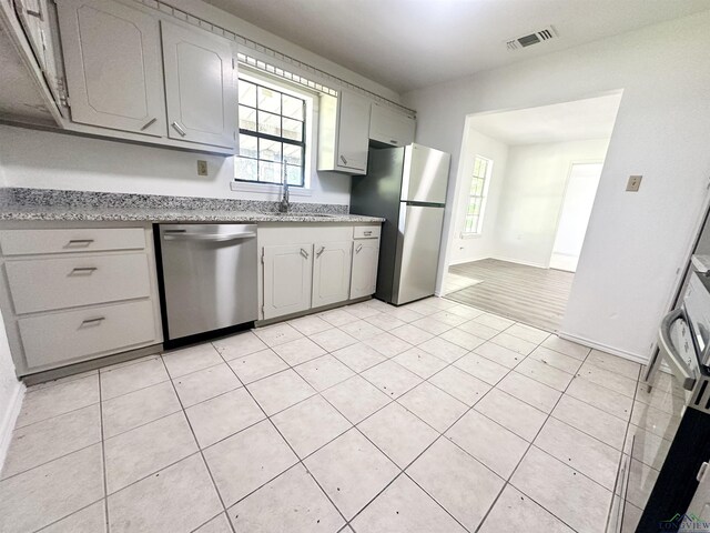 1435 Tom Smith Rd, Harleton, TX 75651 - kitchen featuring appliances with stainless steel finishes, gray cabinetry, and healthy amount of natural light