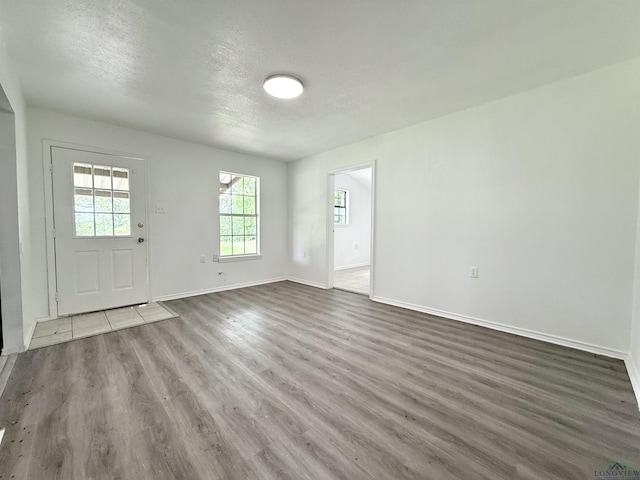 1435 Tom Smith Rd, Harleton, TX 75651 - unfurnished living room with wood finished floors, baseboards, and a textured ceiling