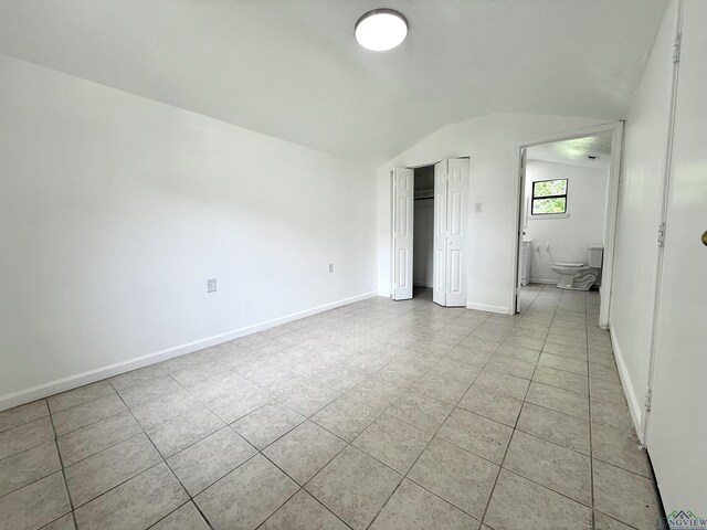 1435 Tom Smith Rd, Harleton, TX 75651 - unfurnished bedroom featuring lofted ceiling, light tile patterned flooring, a closet, and baseboards