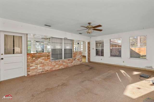 unfurnished living room featuring carpet flooring, ceiling fan, and a wealth of natural light