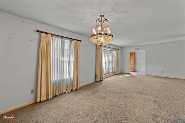 carpeted spare room with a chandelier