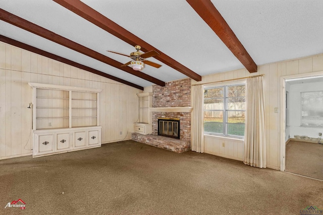 unfurnished living room featuring dark colored carpet, lofted ceiling with beams, a brick fireplace, ceiling fan, and a textured ceiling