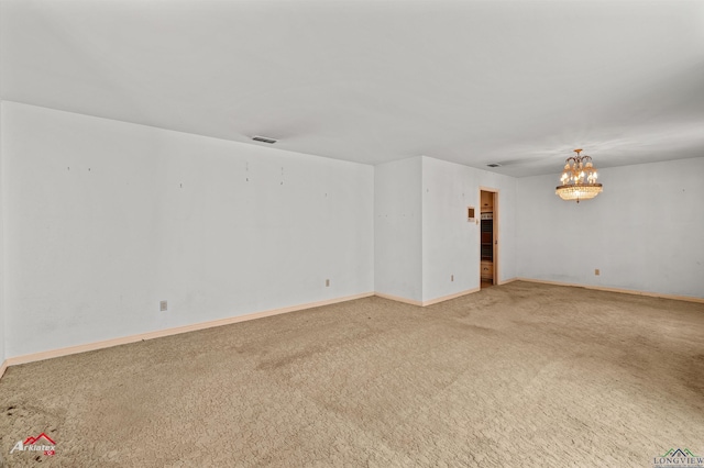 carpeted empty room featuring a notable chandelier