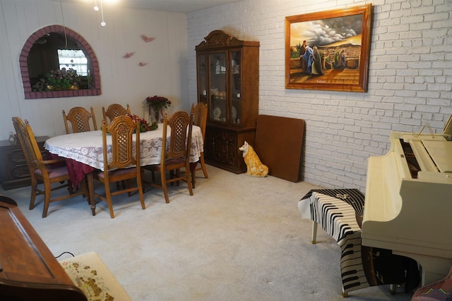 carpeted dining room featuring brick wall