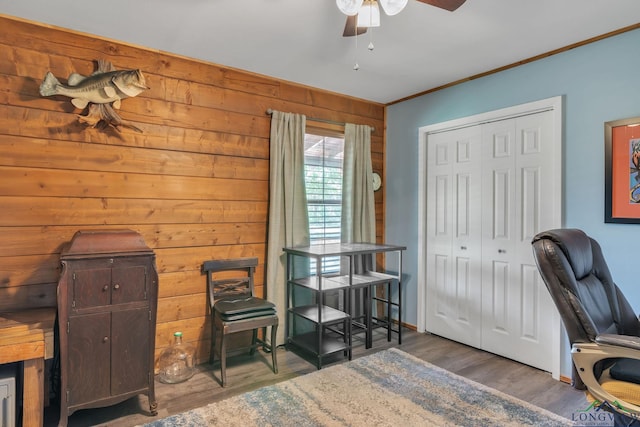 office space with ornamental molding, ceiling fan, wood finished floors, and wood walls