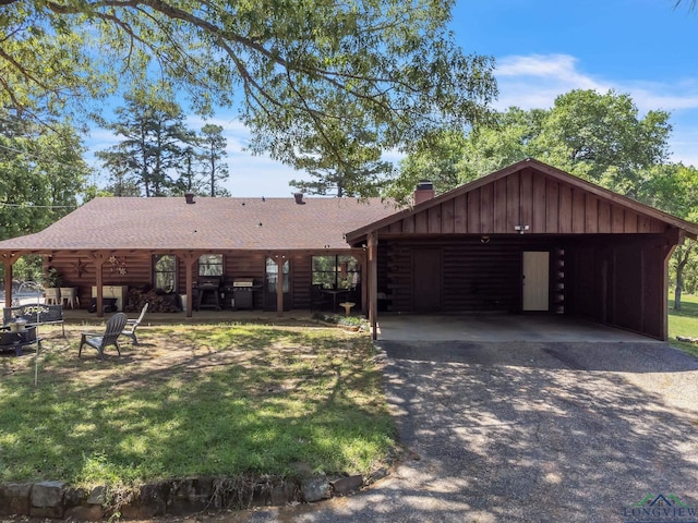 view of front of house featuring roof with shingles, driveway, board and batten siding, and log exterior