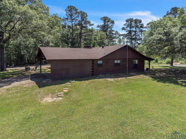 view of side of home with a yard, roof with shingles, and log siding