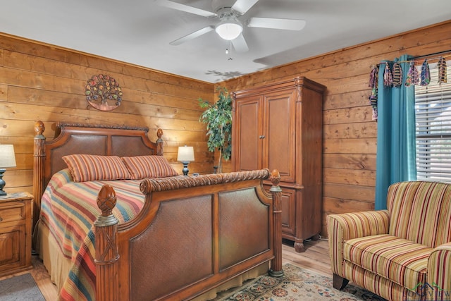 bedroom featuring wooden walls, light wood-style flooring, and ceiling fan