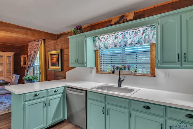 kitchen with a peninsula, green cabinetry, stainless steel dishwasher, and a sink
