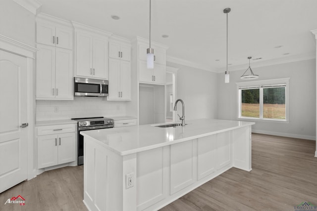 kitchen with sink, white cabinetry, hanging light fixtures, appliances with stainless steel finishes, and a kitchen island with sink