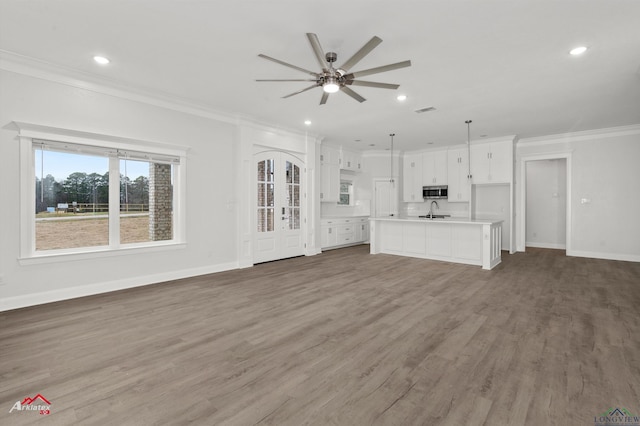 unfurnished living room with dark wood-type flooring, french doors, sink, ornamental molding, and ceiling fan