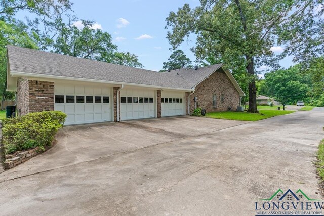 1805 Greenway St, Gilmer, TX 75644 - view of side of home featuring brick siding, concrete driveway, a shingled roof, an attached garage, and a lawn