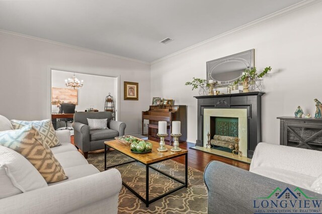 1805 Greenway St, Gilmer, TX 75644 - living room with ornamental molding, wood finished floors, a chandelier, and a fireplace with flush hearth