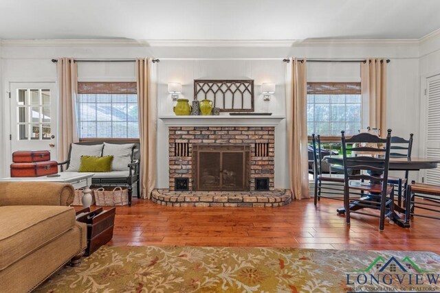 1805 Greenway St, Gilmer, TX 75644 - living room featuring hardwood / wood-style floors, crown molding, healthy amount of natural light, and a brick fireplace