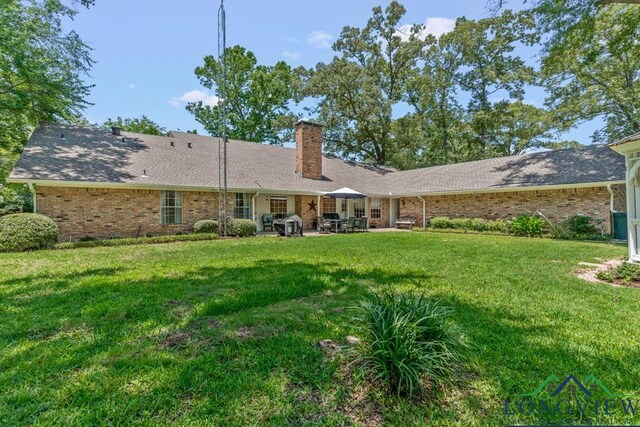 1805 Greenway St, Gilmer, TX 75644 - back of property with a chimney, brick siding, a yard, and a patio