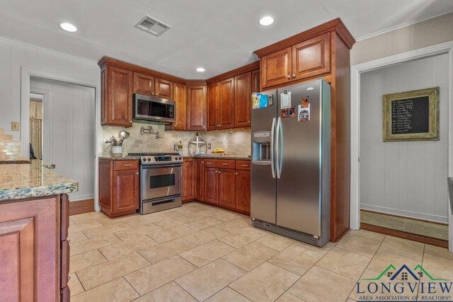 1805 Greenway St, Gilmer, TX 75644 - kitchen featuring appliances with stainless steel finishes, light stone countertops, decorative backsplash, ornamental molding, and brown cabinets