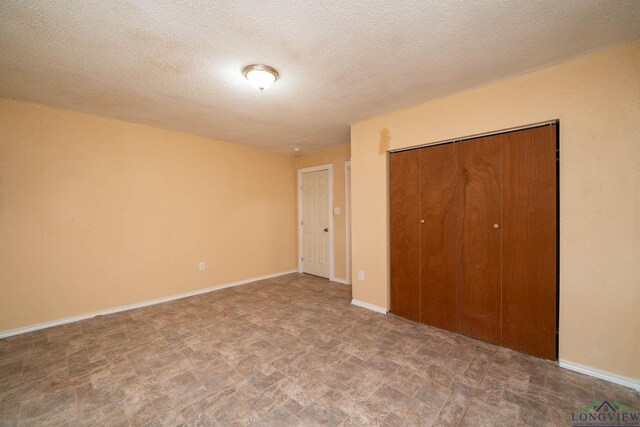 809 Herbert St, Marshall, TX 75670 - unfurnished bedroom with baseboards, a closet, and a textured ceiling