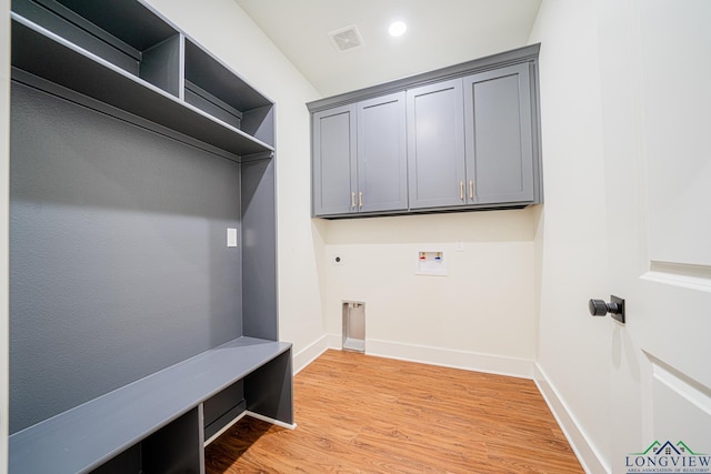 laundry room with electric dryer hookup, cabinets, light hardwood / wood-style flooring, and washer hookup