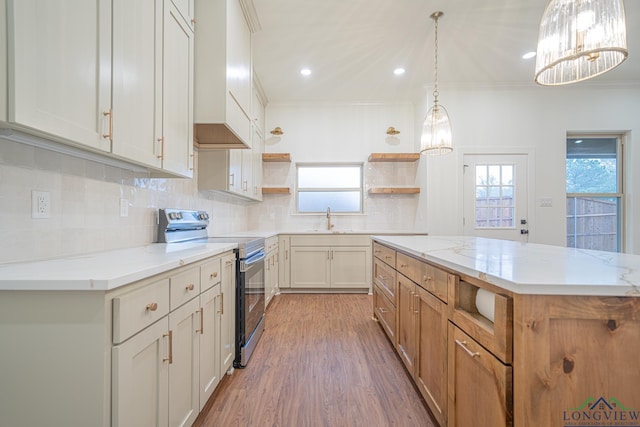 kitchen featuring electric stove, light stone counters, a center island, and sink