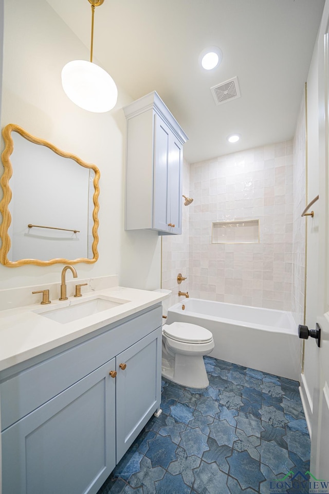 full bathroom with vanity, tiled shower / bath, and toilet