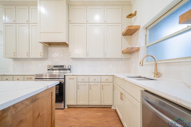 kitchen featuring light stone countertops, sink, stainless steel appliances, tasteful backsplash, and light hardwood / wood-style flooring