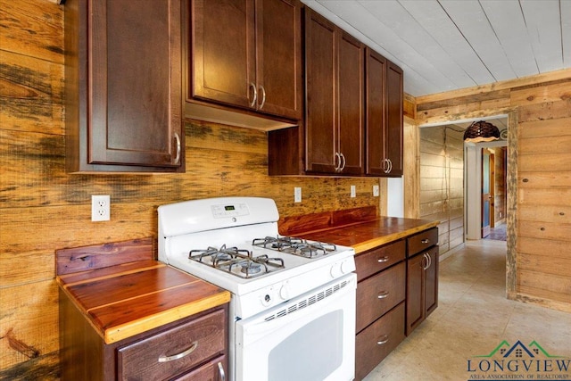 1150 Fm 139, Joaquin, TX 75954 - kitchen with white gas range, dark brown cabinets, wooden walls, light tile patterned flooring, and wood ceiling