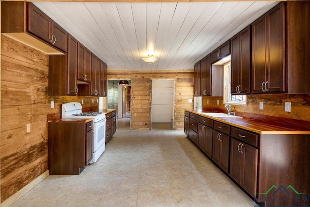 1150 Fm 139, Joaquin, TX 75954 - kitchen with white range with gas stovetop, wood walls, light countertops, and light floors