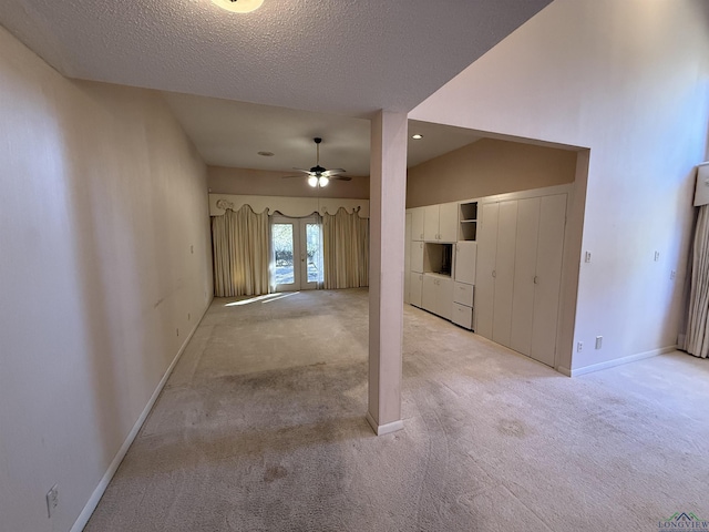 unfurnished room with ceiling fan, a textured ceiling, and light colored carpet