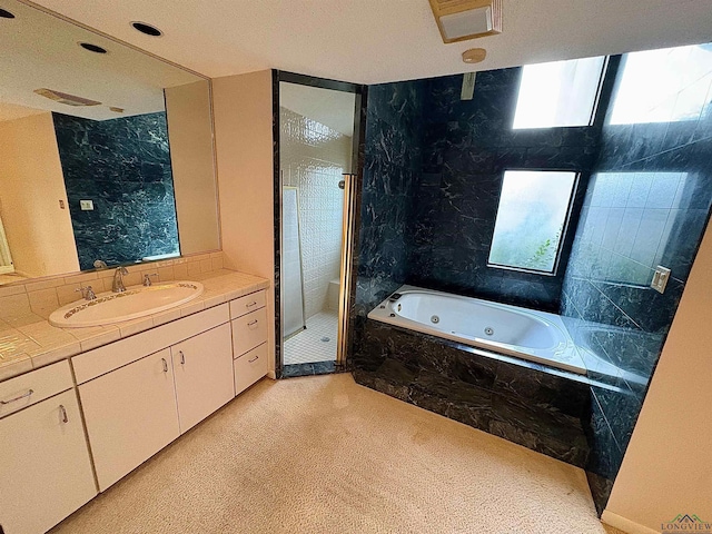 bathroom with vanity and shower with separate bathtub