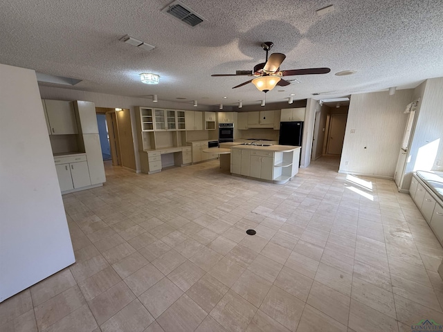 kitchen featuring ceiling fan, a kitchen island, a textured ceiling, and black appliances