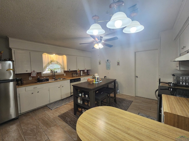 kitchen with appliances with stainless steel finishes, butcher block countertops, white cabinetry, sink, and a textured ceiling