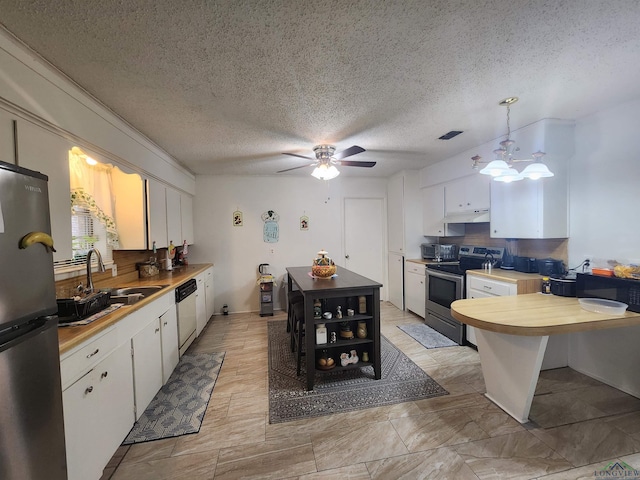 kitchen featuring sink, stainless steel appliances, white cabinets, a textured ceiling, and decorative light fixtures