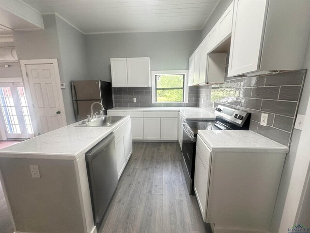 kitchen featuring crown molding, wood finished floors, a sink, stainless steel appliances, and white cabinetry