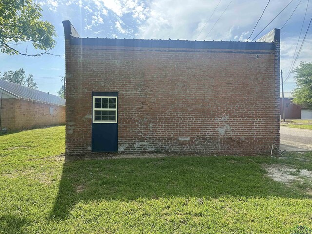 view of property exterior with a yard and brick siding